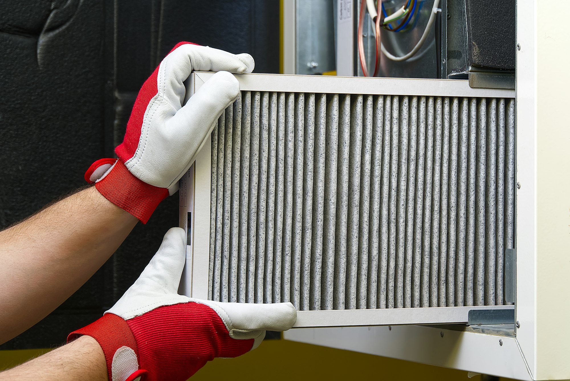 A mans hands that are replacing the condition air filter