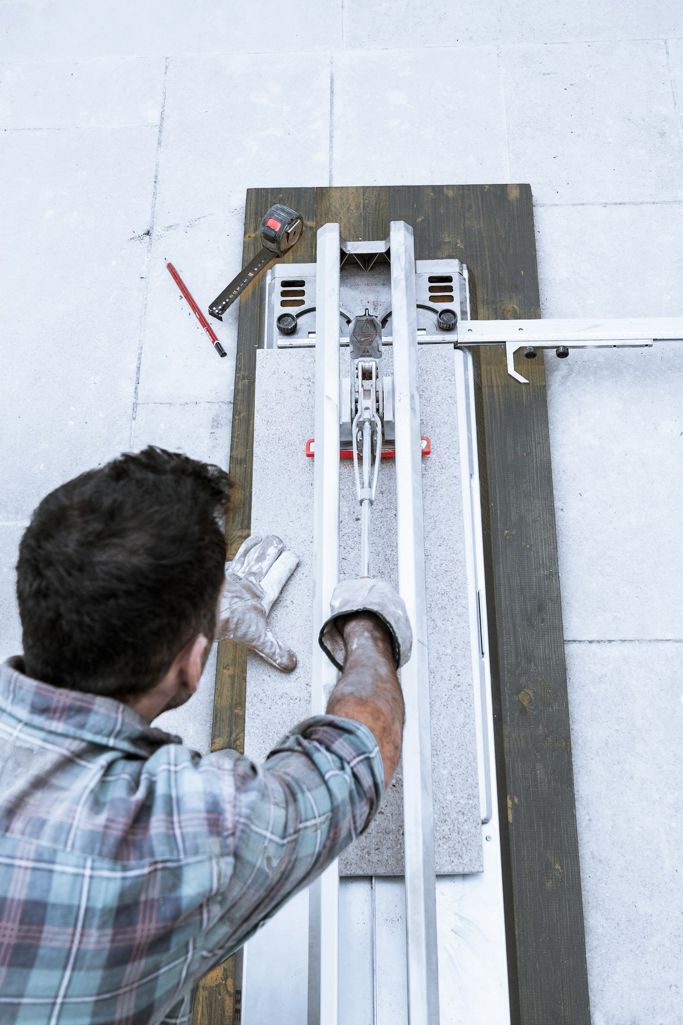 A worker cuts a tile with a professional tile cutter.