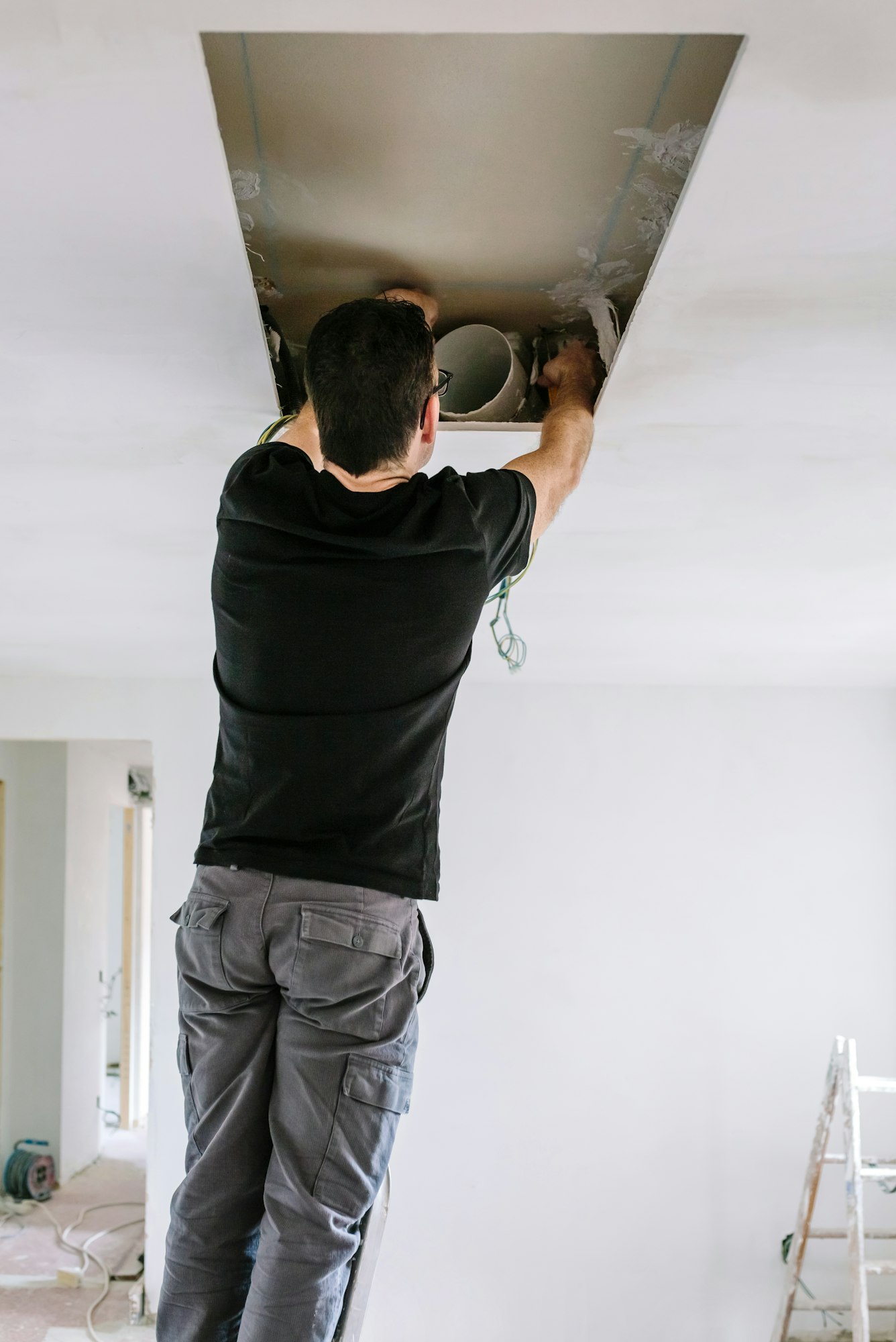 Man preparing extractor hood installation on kitchen ceiling